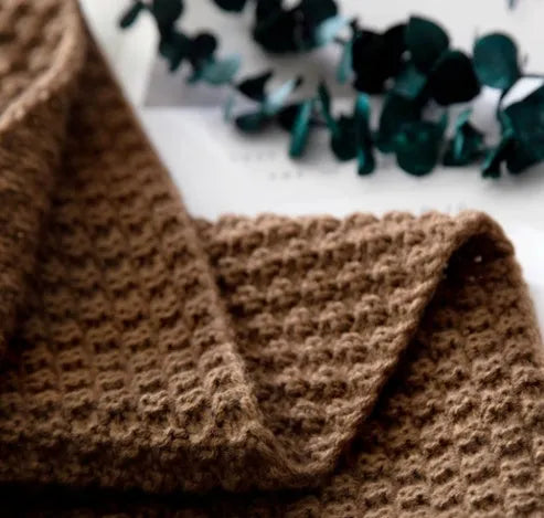 Acrylic knitted fringed blanket in beige colour on a sofa, showing texture and size.
