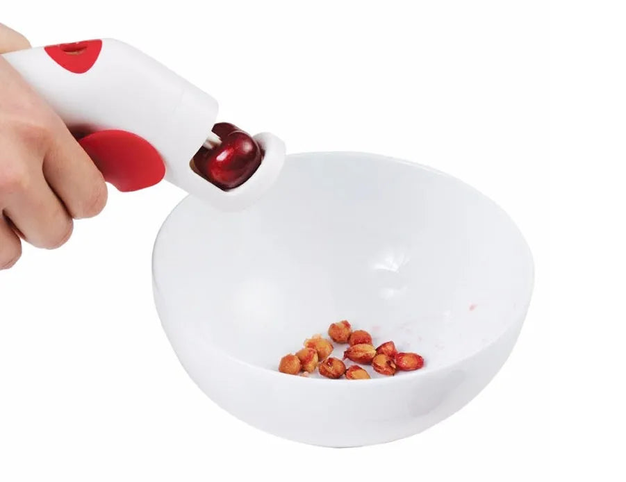 Red and white stainless steel manual cherry kernel remover pitter on a clean surface