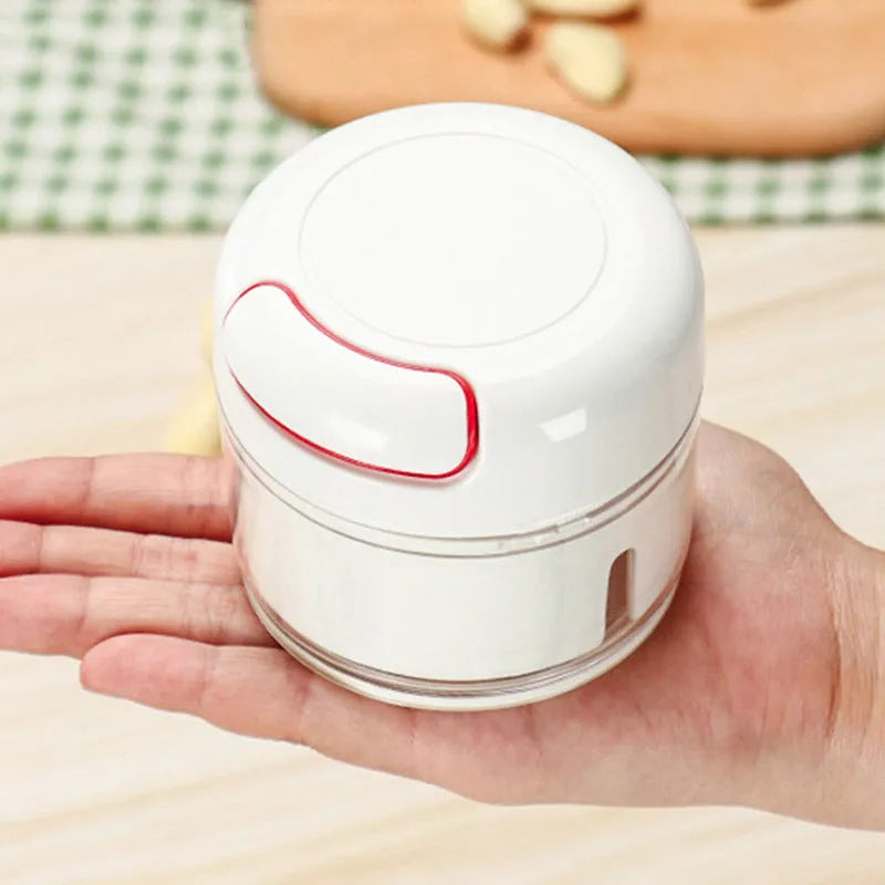 White and silver manual food chopper with stainless steel blades on a kitchen countertop.