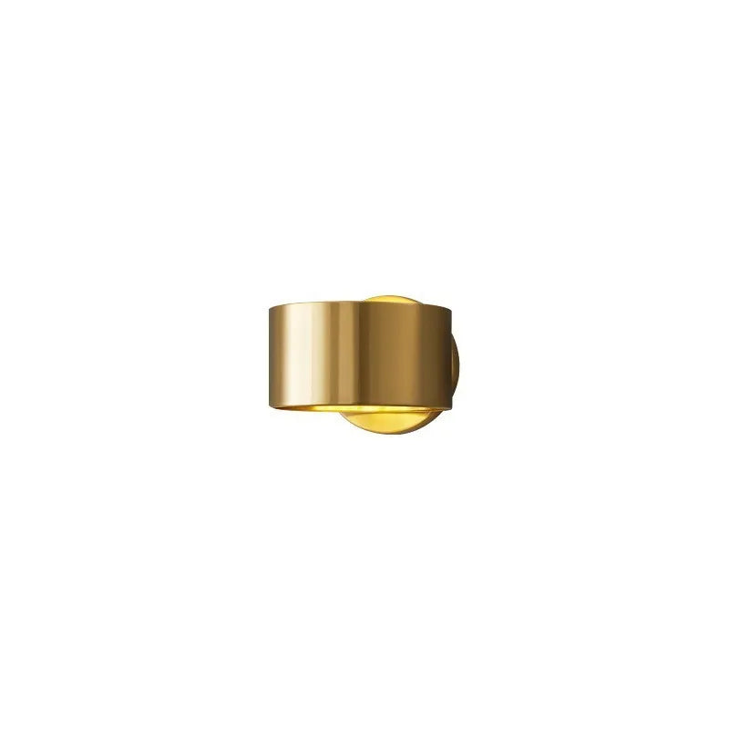 Modern minimalist copper wall lamp in gold finish mounted on a wall.