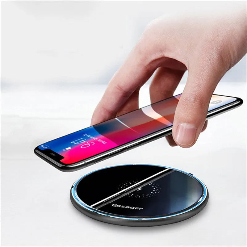 Black Qi wireless charging pad on a desk with blue LED light indicating active charging.