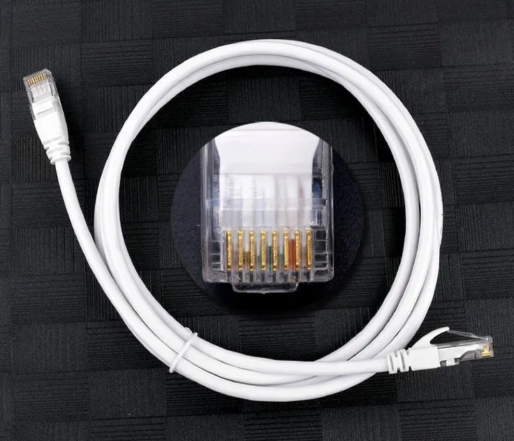 White Cat6 network cable with RJ-45 connectors on both ends lying on a flat surface