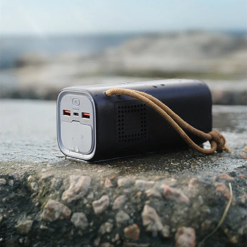Black portable power bank with solar panel, showing USB ports and car charging socket