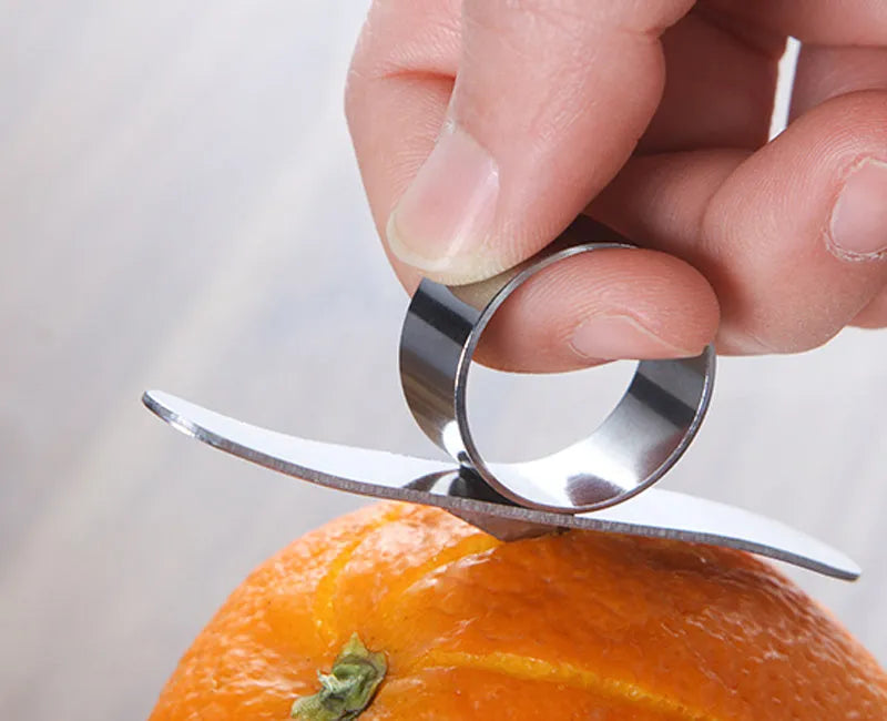 Silver stainless steel citrus fruit peeler with a ring-shaped handle on a kitchen surface.