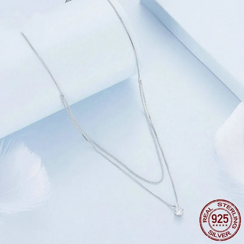 Close-up of a double-layer sterling silver necklace with a pearl-style chain, showing its layered design and silver finish.