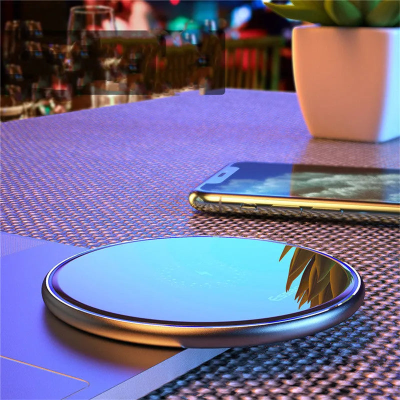 Black Qi wireless charging pad on a desk with blue LED light indicating active charging.