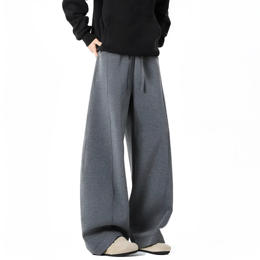 Men’s relaxed fit dark gray trousers with drawstring waist and belt on model