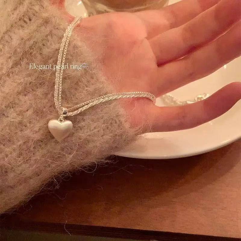 Double layer brushed heart shaped pendant necklace on adjustable silver tone chain.