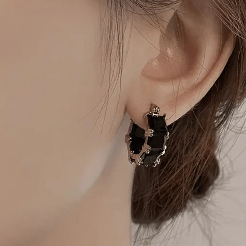 Gold geometric U-shaped women's earrings with a round black crystal zirconium stone.