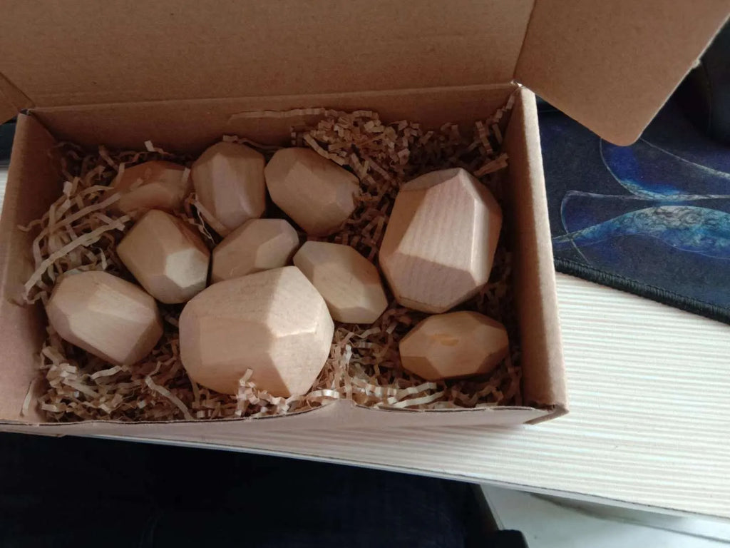 Wooden building block set with coloured and natural stone stacks on a table, suitable for children aged 4-6