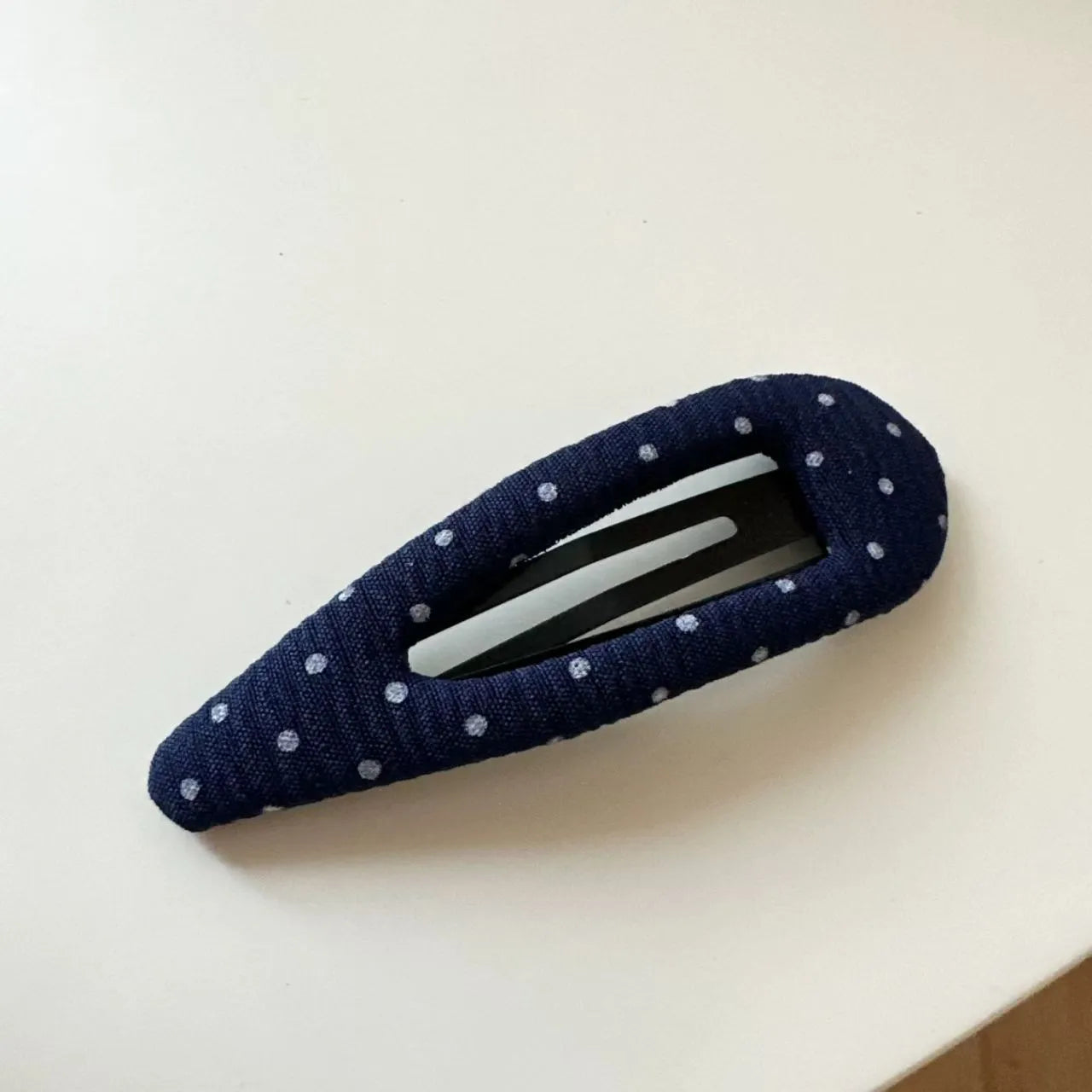 Dark denim barrette with white polka dots in a triangle shape next to a water drop shaped barrette.