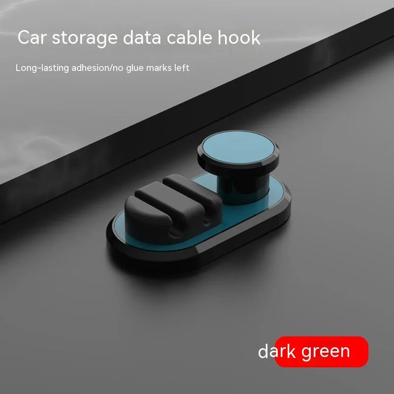 Dark green ABS silicone car cable hook with adhesive backing for organising data cables on a dashboard.