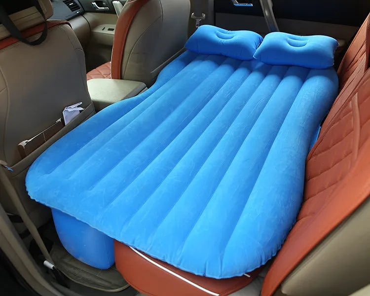 Inflatable car bed with flocked surface folded beside two pillows in storage bag for vehicle sleeping
