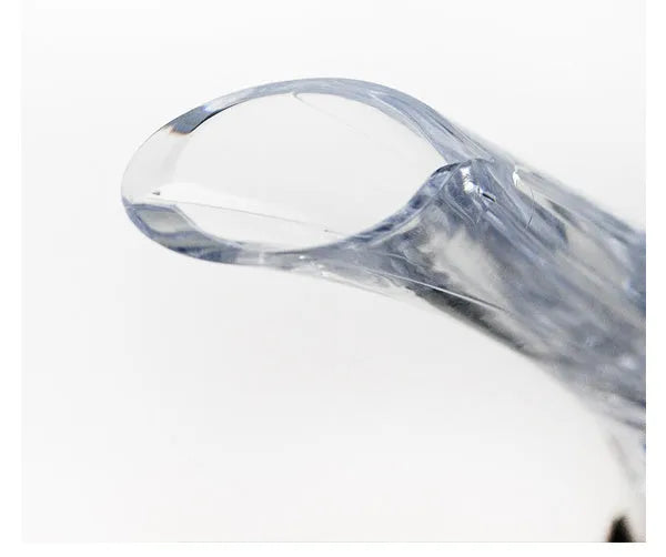 A clear acrylic wine aerator with a stainless steel filter, shown next to a wine glass.