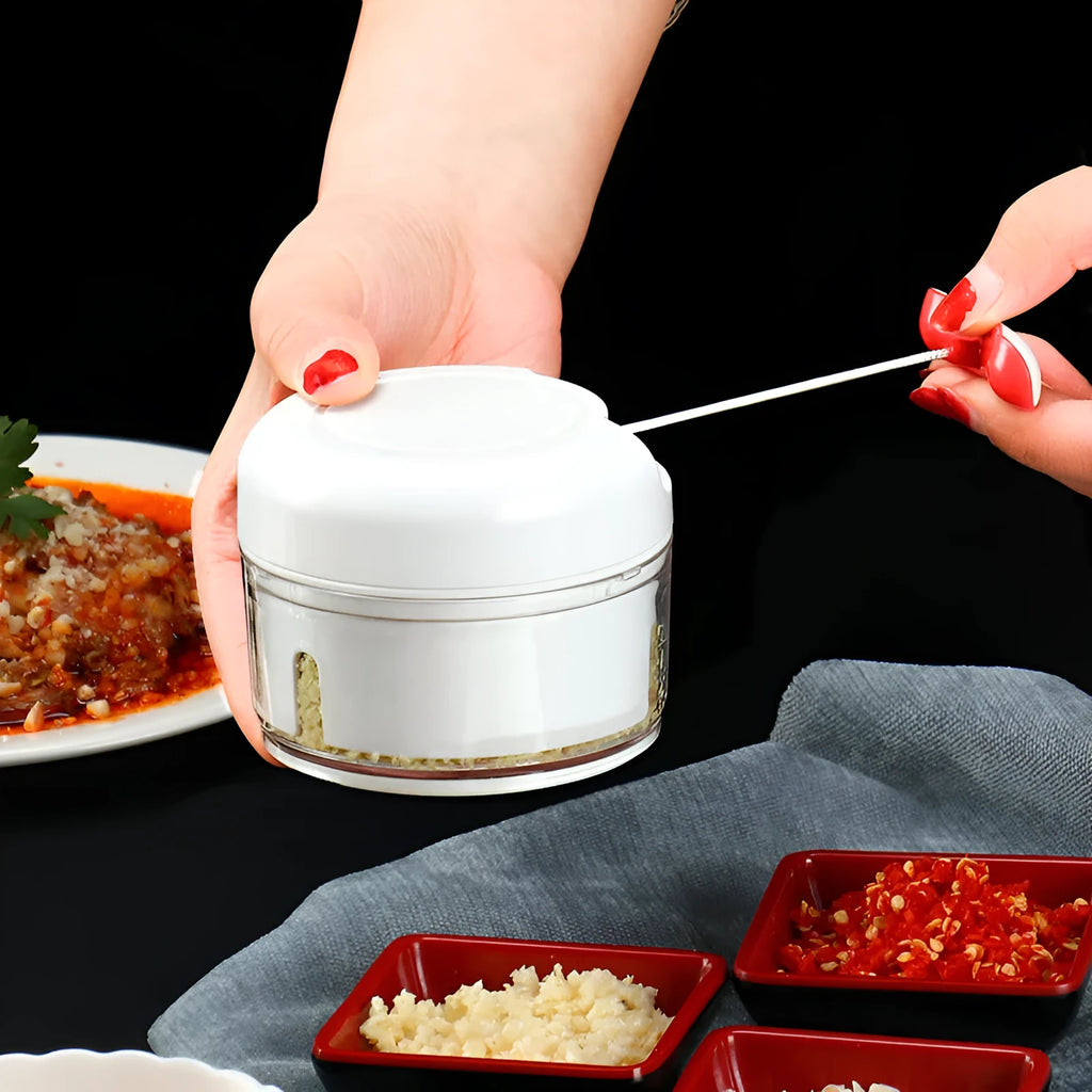 White and silver manual food chopper with stainless steel blades on a kitchen countertop.