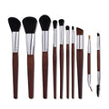 10 brown makeup brushes with wooden handles and nylon bristles laid out on a flat surface