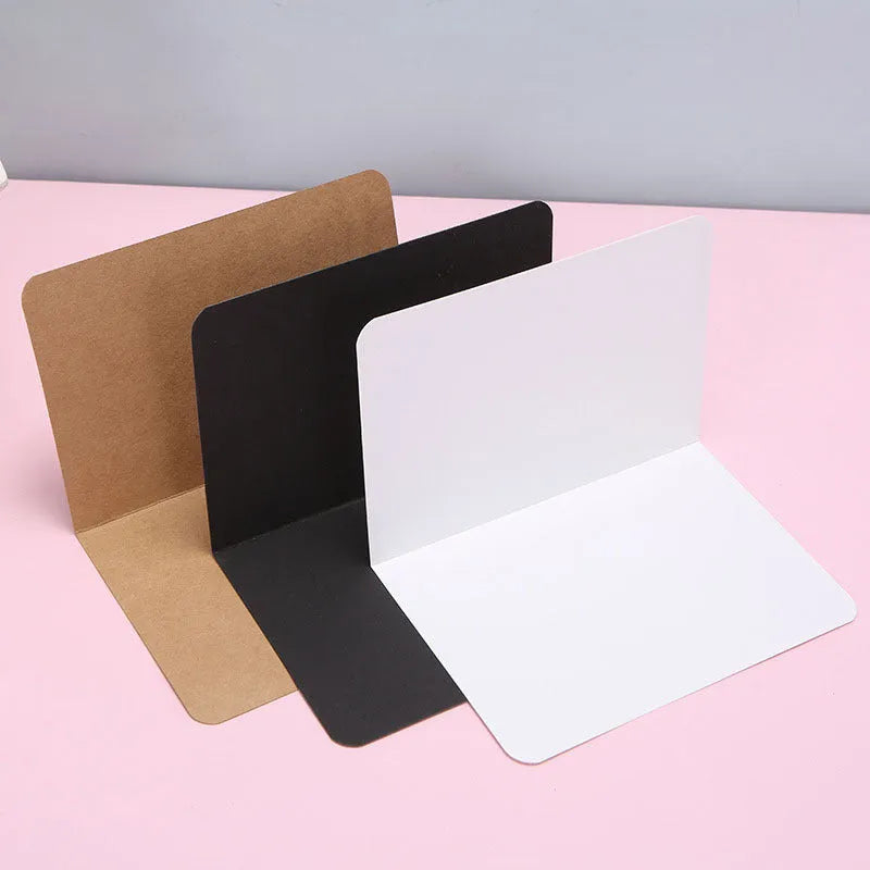 Pack of 100 blank folded kraft greeting cards in 10x15cm size, showing black, brown, and white colour options.