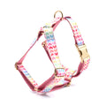 Pink dog harness with a gold buckle and colourful heart-shaped stone decoration on an adjustable polyester strap.