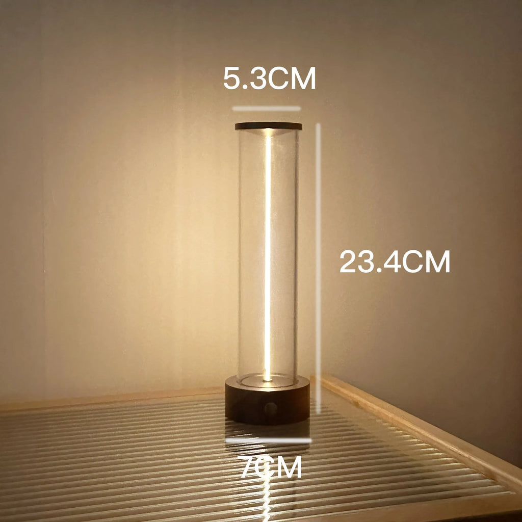 Tall cylindrical frosted glass USB rechargeable LED night light with a magnetic base on a wooden surface.