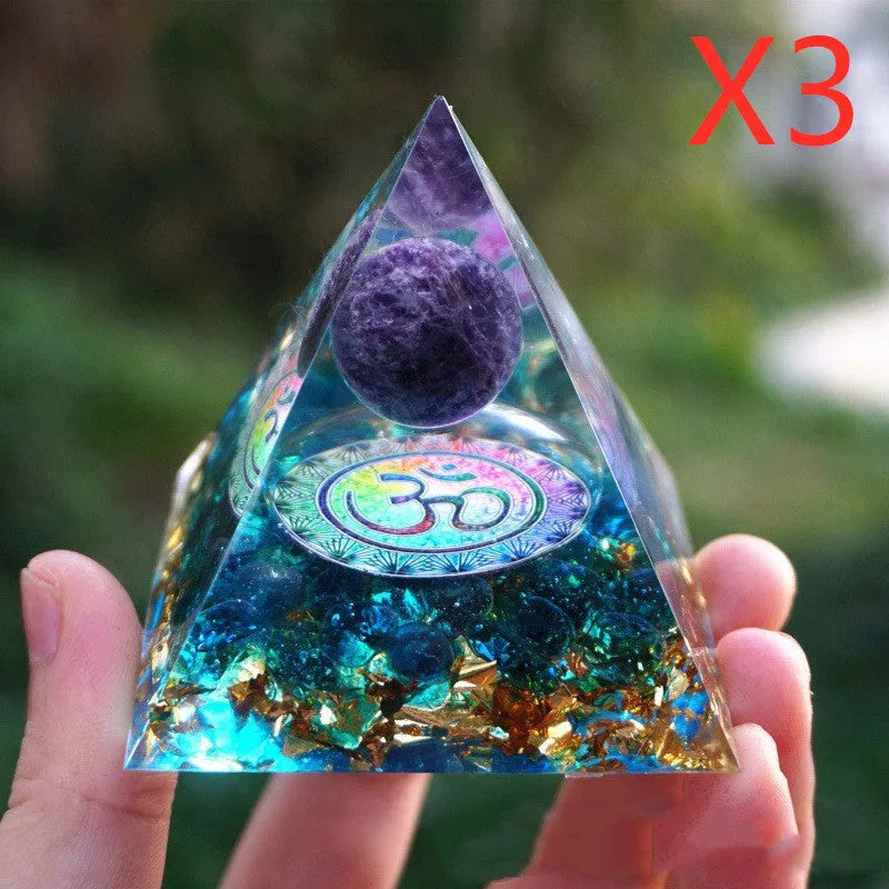 Clear epoxy resin pyramid ornament with natural crystal gravel inside on a wooden surface.