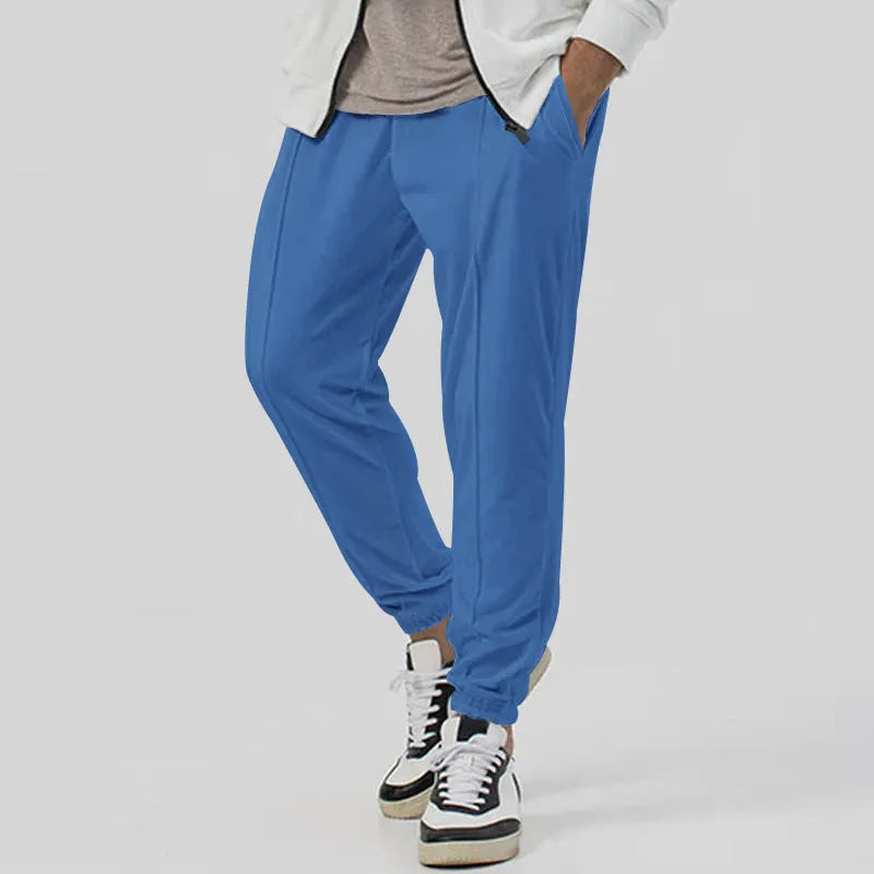 Man wearing grey loose tapered cotton blend track sweatpants with a straight leg.