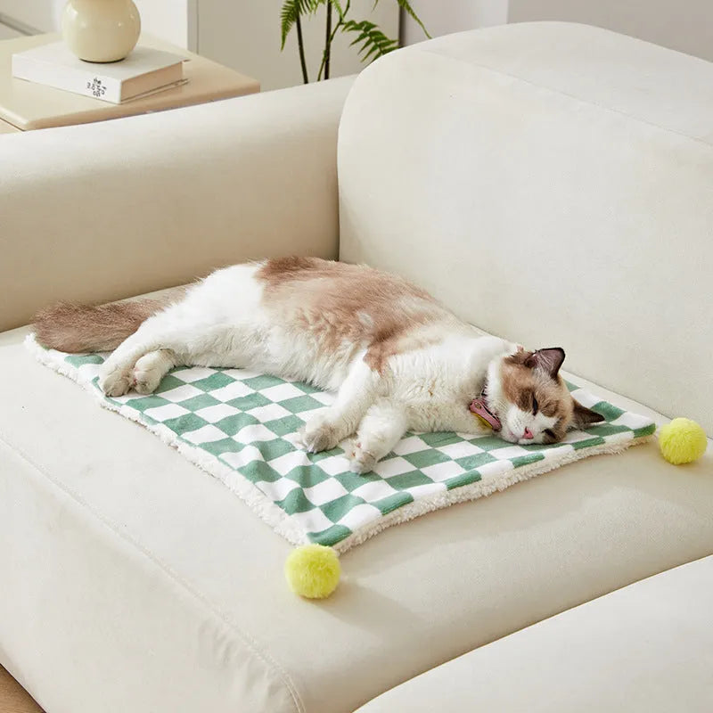 Soft plaid pattern pet blanket with fur ball decoration on a sofa