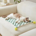 Soft plaid pattern pet blanket with fur ball decoration on a sofa