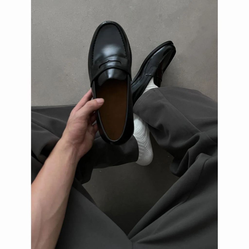 Men's black leather loafers with stitched seams, square heel, and vulcanised rubber sole on display