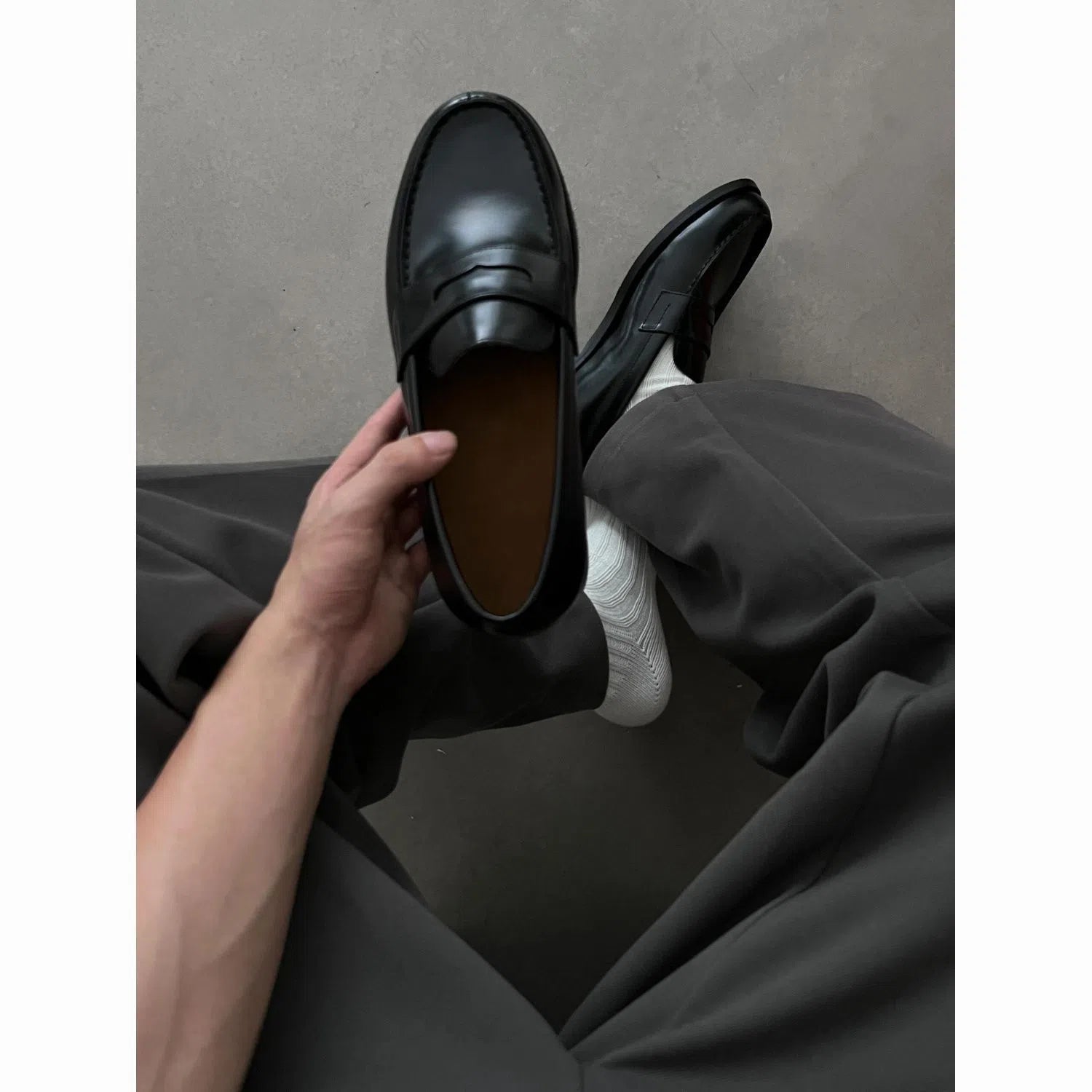 Men's black leather loafers with stitched seams, square heel, and vulcanised rubber sole on display