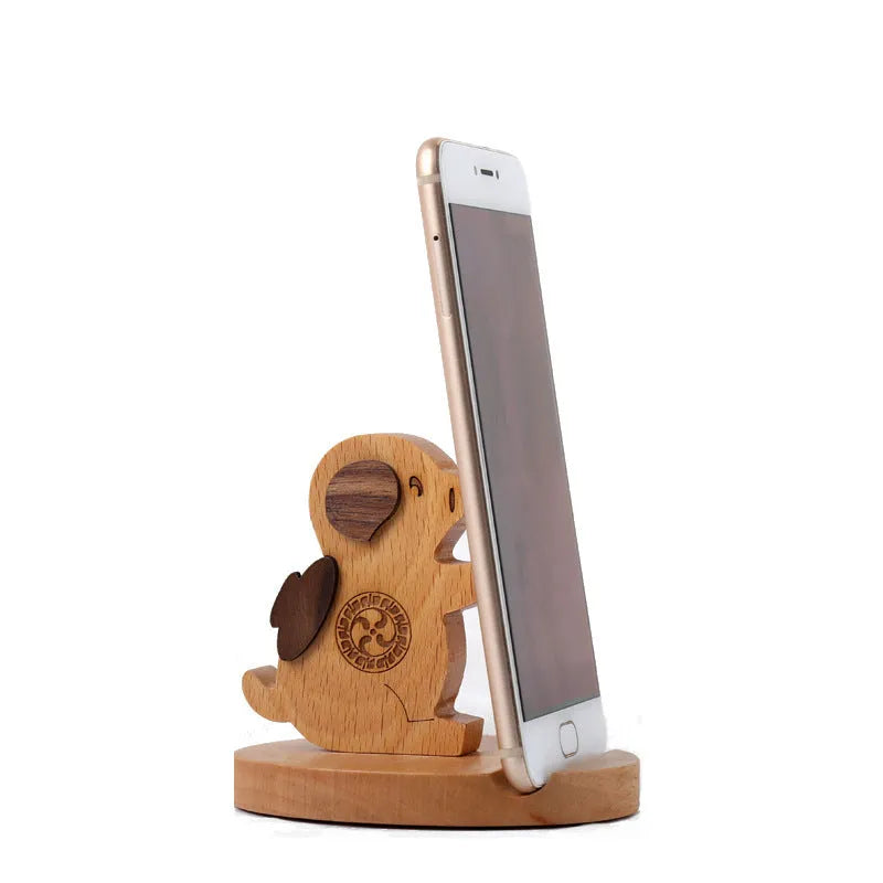 Beech wood and resin lazy bracket mobile phone holder in an animal design style on a desk.
