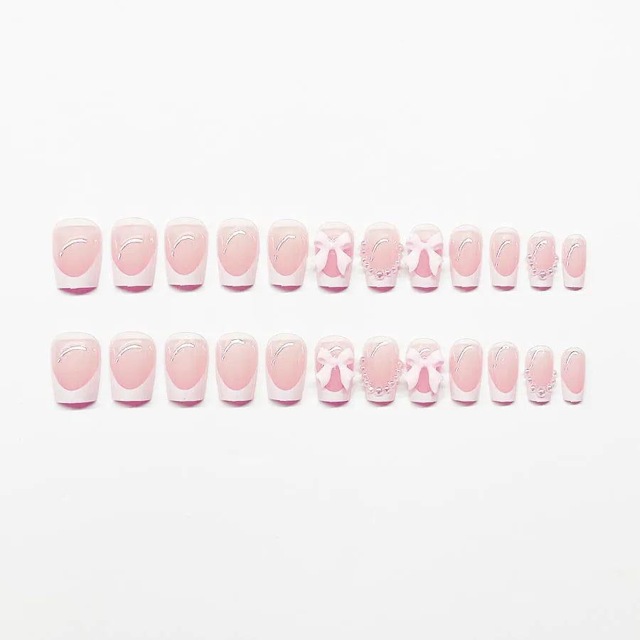 Artificial press-on nails with French manicure style showing bow patterns and tulip designs on short European square nails