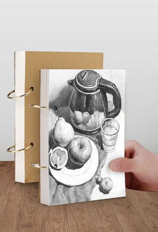 8K thickened sketchbook open on a table with marker drawings, showing linen and black card cover options.