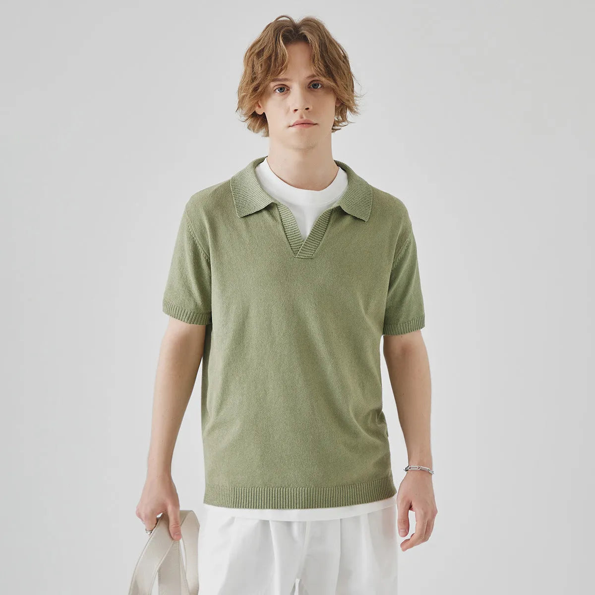 Man's short-sleeved knitted polo t-shirt in a solid colour on a hanger.