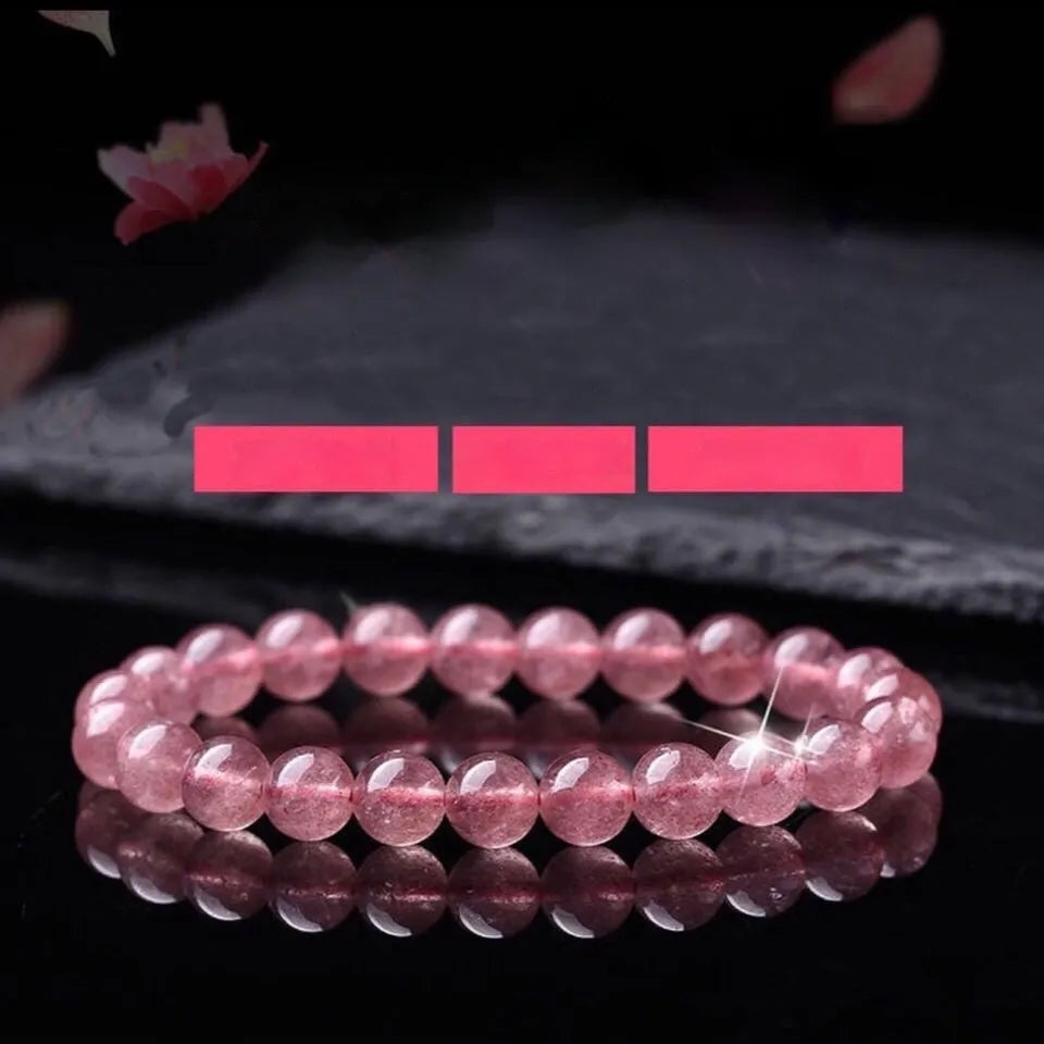 Women's strawberry quartz crystal bracelet with polished beads on a wrist.