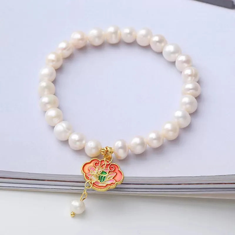 Natural freshwater pearl bracelet with vintage goldfish pendant and lotus motif on white background