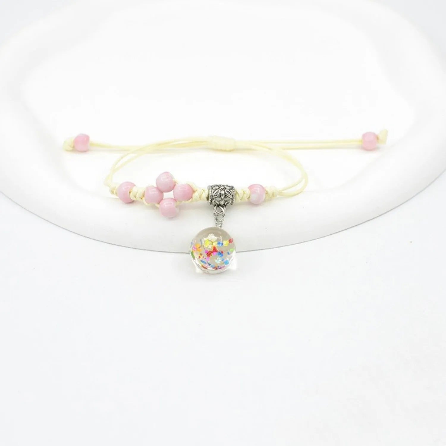 Close-up of a hand-woven glass bracelet with large 1.4cm beads containing real dried flowers in various colours.
