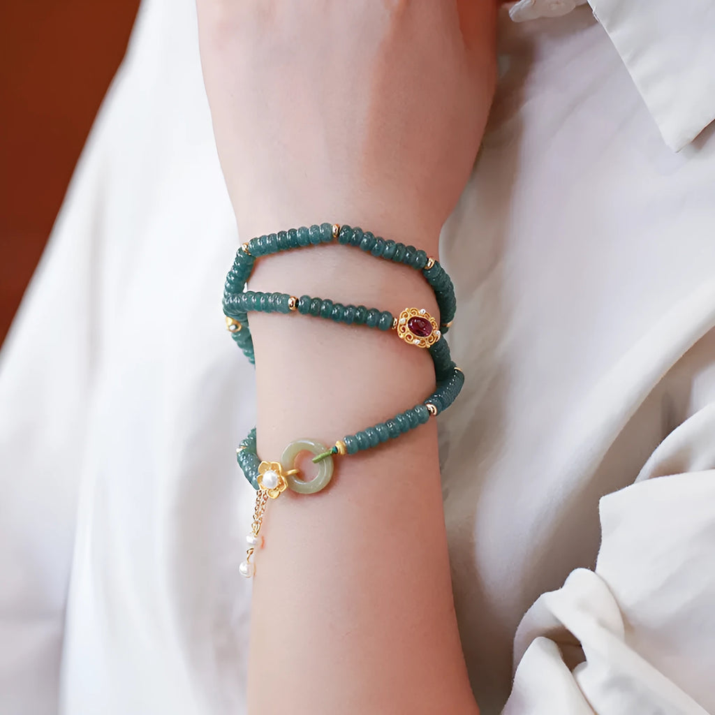 Blue water abacus and jade bead bracelet with tourmaline rings and pearl accents on a wrist.