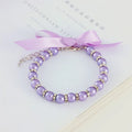 Small dog wearing adjustable diamond pearl necklace with rhinestones and ribbon bow in blue colour