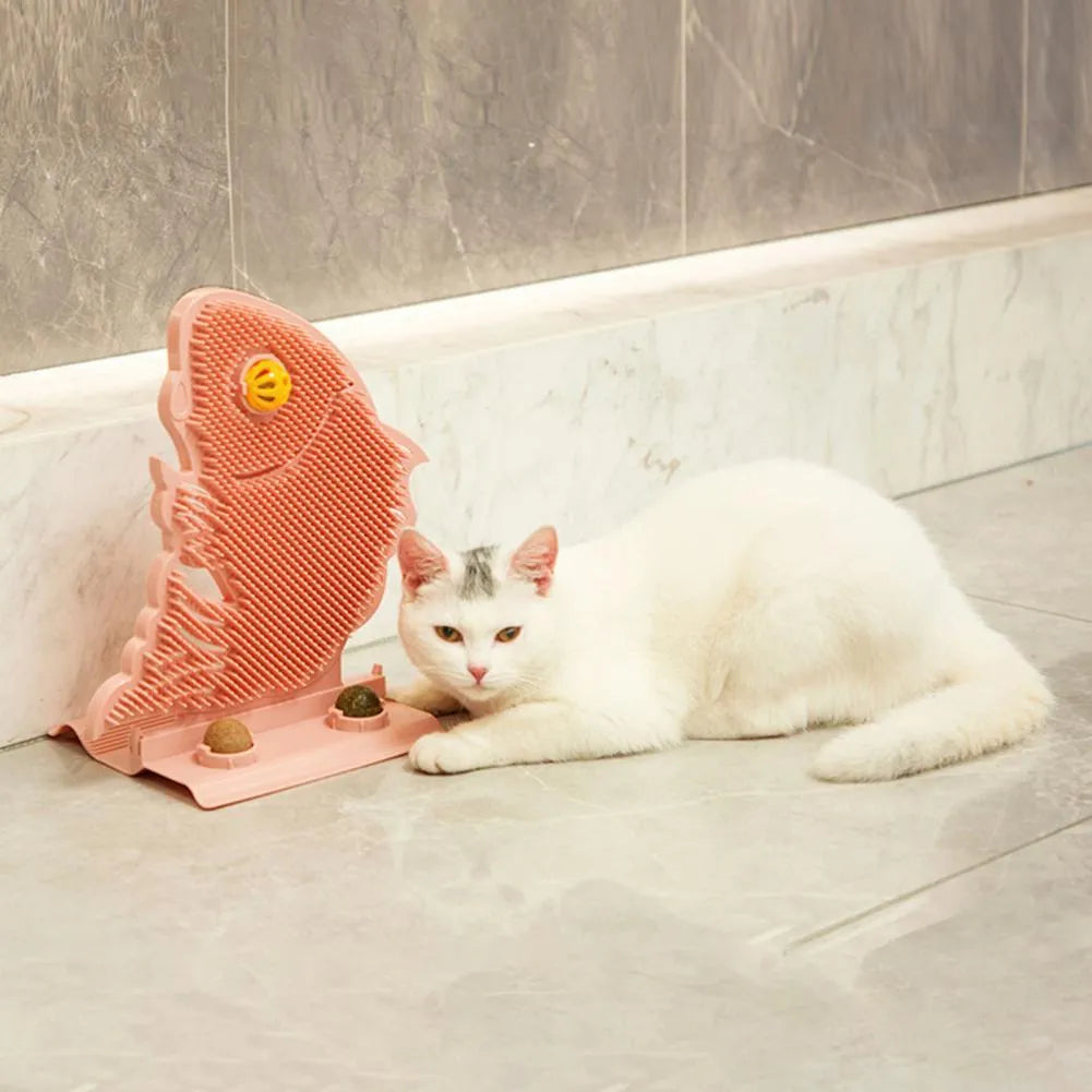 Blue plastic fish-shaped cat wall scratcher with brush, two green catnip balls, a bell, and a mounting base.