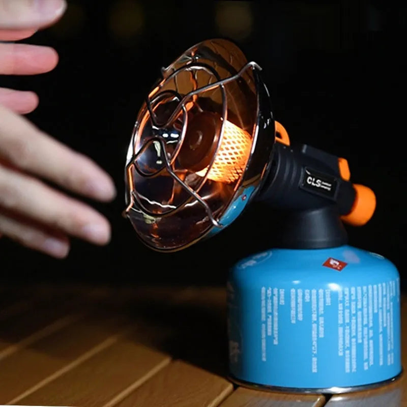 Black and orange portable outdoor heating stove with automatic ignition on a camping table.