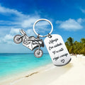 Stainless steel motorcycle-themed keychain on a velvet flannel bag