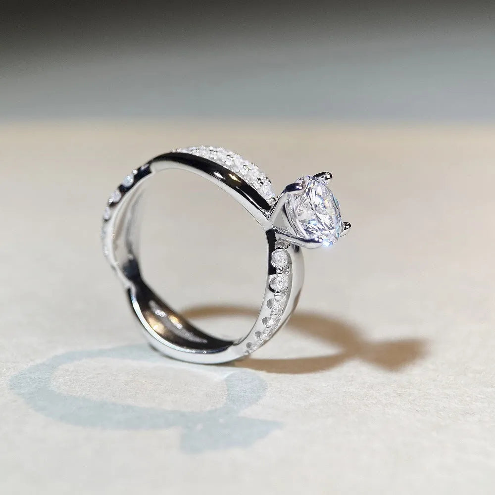 Silver geometric cross ring with a 1-karat moissanite stone on a twisted band.