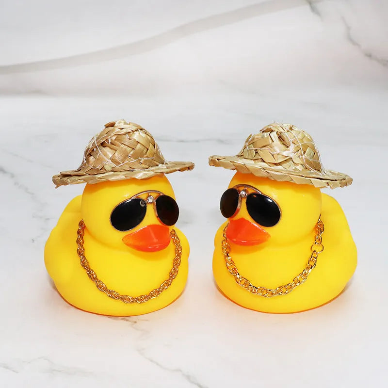 Yellow duck cartoon character wearing a straw hat, a car dashboard ornament with miniature sunglasses accessory.