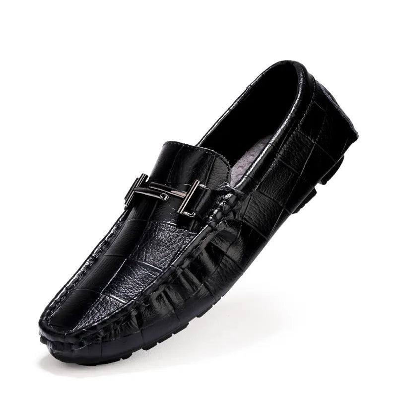 Men's black leather casual shoes with a silver belt buckle closure on a flat rubber sole.