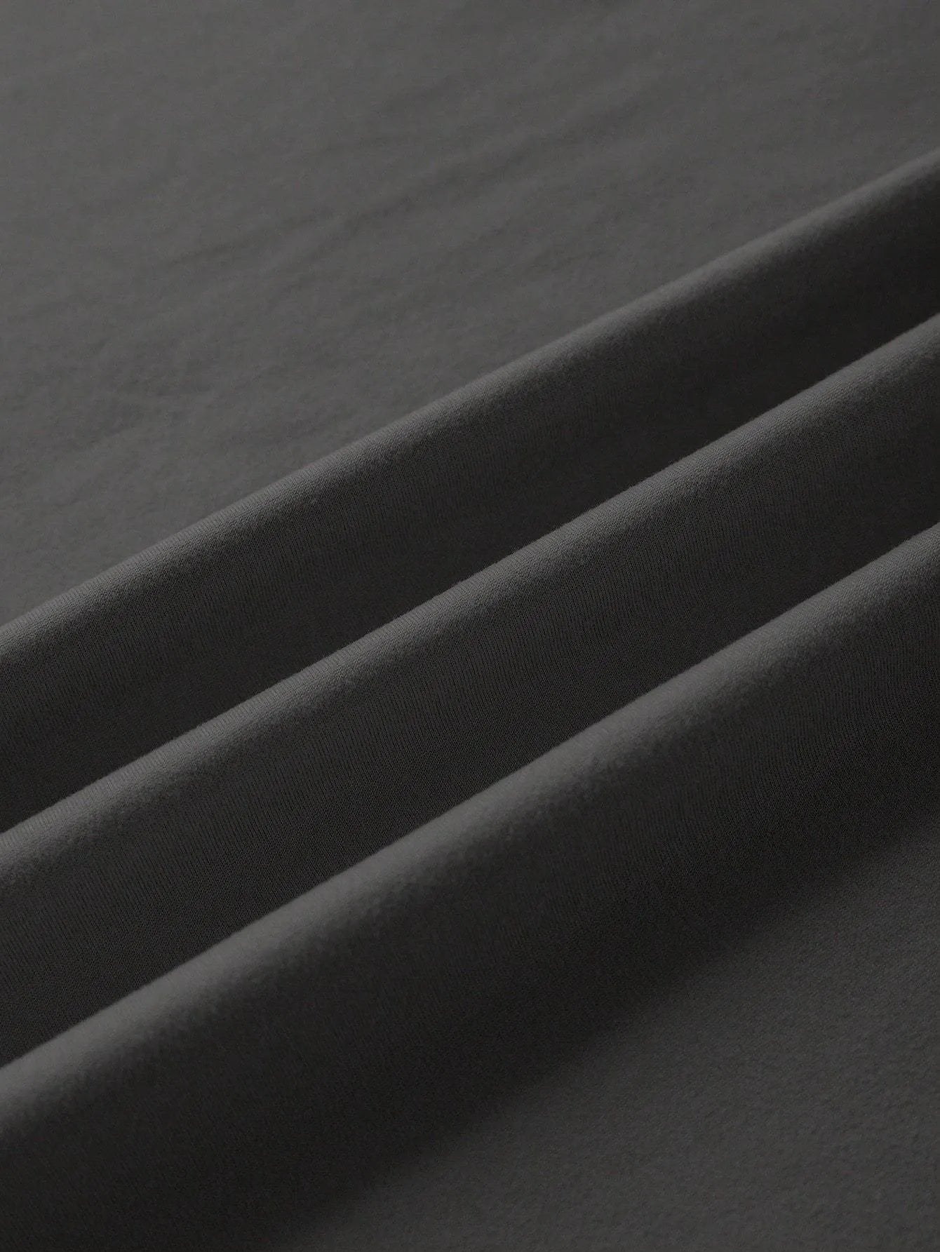 Loose short-sleeve cotton T-shirt on a hanger, showing round neckline, available in black, green, grey, and orange.