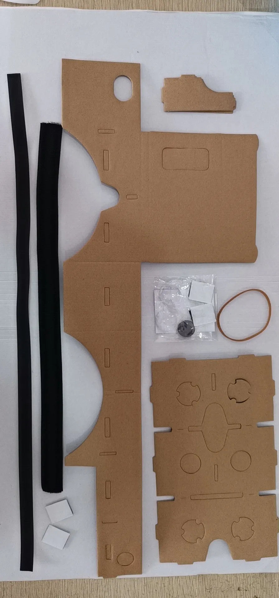 Pink and white foldable VR cardboard glasses for mobile phones, showing 3D lenses and rubber band.