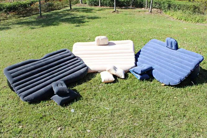 Black inflatable car bed with flocked surface, shown with storage bag and pillows, ready for use in a vehicle.