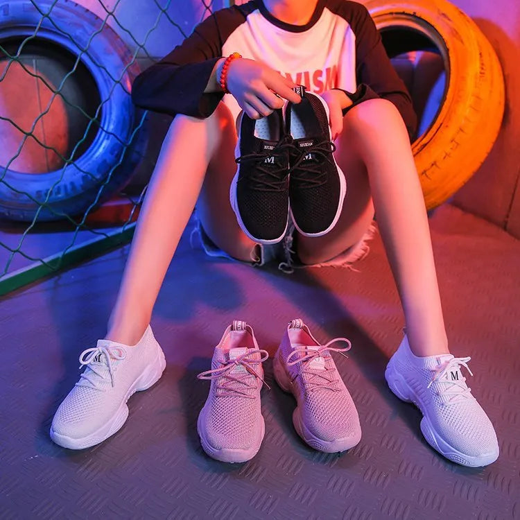 Women's white low-top woven sneakers with thick rubber sole and elastic front strap.