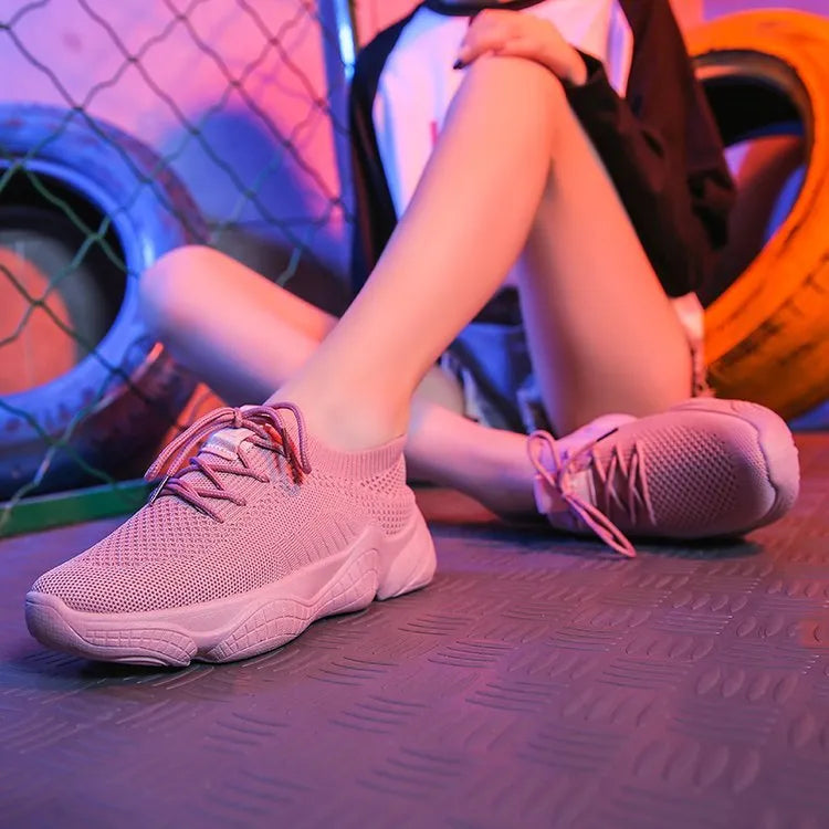 Women's white low-top woven sneakers with thick rubber sole and elastic front strap.