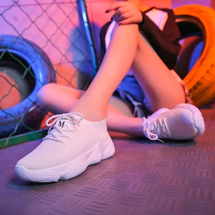 Women's white low-top woven sneakers with thick rubber sole and elastic front strap.